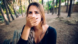 Portrait Of Young Woman Covering Mouth In Forest