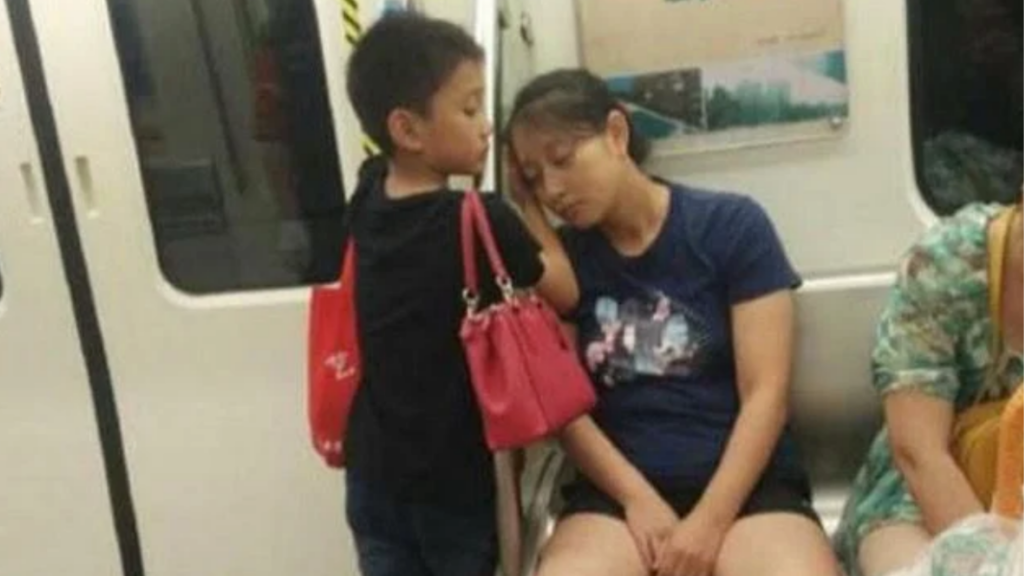 Niño pone sus manos como almohada para que duerma su mamá en el metro