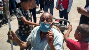 Pequeños llevan a su abuelito en carriola para que reciba su vacuna