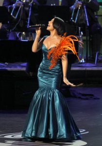 Ángela Aguilar vestido azul con pluma.