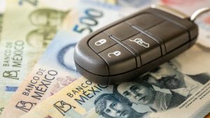 Car keys and Mexican pesos. Business concept. Car insurance, Parking zone, transportation regulations, Leasing, Car loan, transportation costs, toll roads. close up