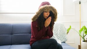 Young woman feeling very cold without heating at home