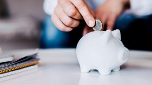 Putting a coin in a white piggy bank at home.
