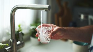 Hand Holding Glass Under Tap for Fresh Drinking Water at Home
