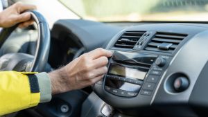 Driver inserting cd in car stereo while driving