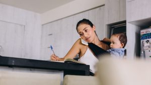 Working mom holding her baby while she writes