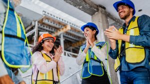Coworkers celebrating and applauding on construction site