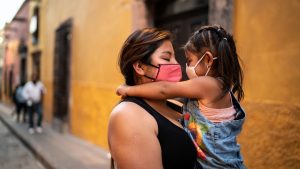 Mother and daughter embracing outdoors - wearing face mask
