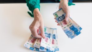 Woman's hands count 500 Mexican pesos on white table