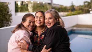 Female Latin friends hugging each other and laughing at home