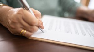 Close-up of document being signed by woman