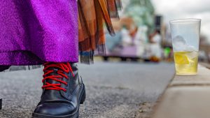 Macro view of a parade participant's boot next to a plastic cup containing some kind of alcoholic beverage