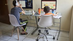 Two boys (8-9, 14-15) e-learning at home during Covid-19 lockdown