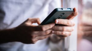 Unrecognizable young man using mobile phone device at home