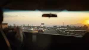 View from car interior driving on highway at sunset with clear skies and distant mountains. Mexico City, Mexico