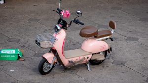 Pink electric scooter parked on stone pavement near Saint John of God Market