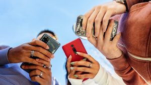 Low angle view of three young people using mobile phones outdoors