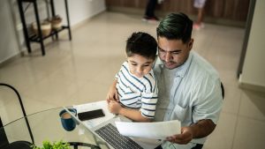 Father working with his son using laptop at home