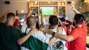 Mexican fans celebrating a goal in soccer game at bar