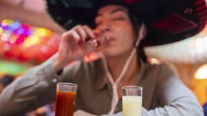 Young tourist sampling the variety of tequilas in Mexico during the country's national holidays, wearing a traditional charro hat.