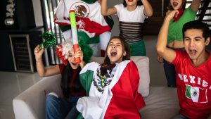 Teenager Latin friends celebrating a goal by the Mexico soccer team at home